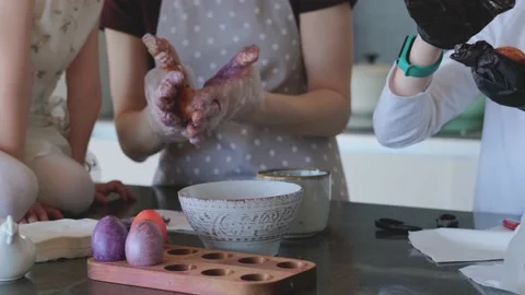Happy Easter. Mom and two cute daughters paint eggs for the traditional spring Stock Footage 189173826