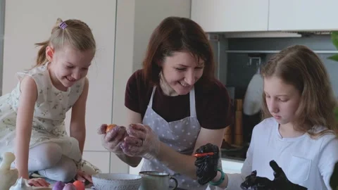 Happy Easter. Mom and two cute daughters paint eggs for the traditional spring Video stock 189662110