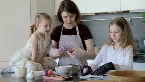 Happy Easter. Mom and two cute daughters paint eggs for the traditional spring Stock Footage 220079591
