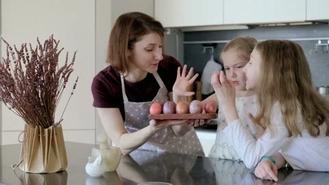 Happy Easter. Mom and two cute daughters paint eggs for the traditional spring Stock Footage 220079789