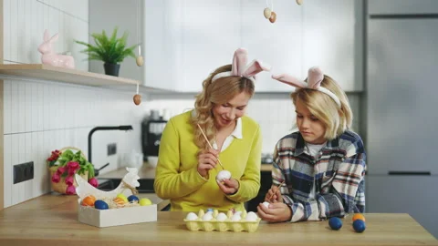 Happy easter. A mother and son in kitchen sitting, painting eggs for traditional Stock Footage 234194441