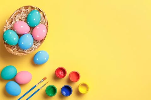 Happy easter. Multi-colored eggs in a basket, brushes and paints. Stock Photos