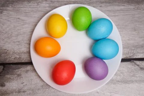Happy Easter. Multicolored eggs on a white plate. All the colors of the rainbow. Stock Photos