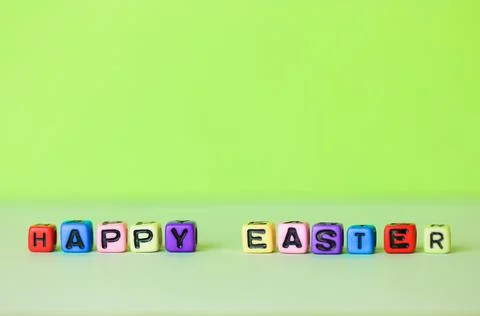 Happy Easter multicolored text on a light green lettuce minimalistic background Stock Photos