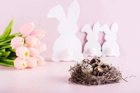 Happy easter nest with quail eggs, white rabbit family and bouquet of flowe.. Stock Photos