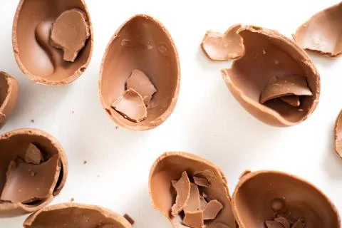 Happy Easter. Open broken destroyed crumbled chocolate eggs on a white Stock Photos