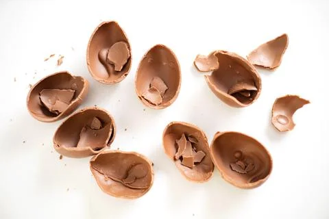 Happy Easter. Open broken destroyed crumbled chocolate eggs on a white Stock Photos