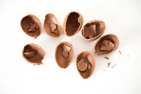 Happy Easter. Open broken destroyed crumbled chocolate eggs on a white Stock Photos