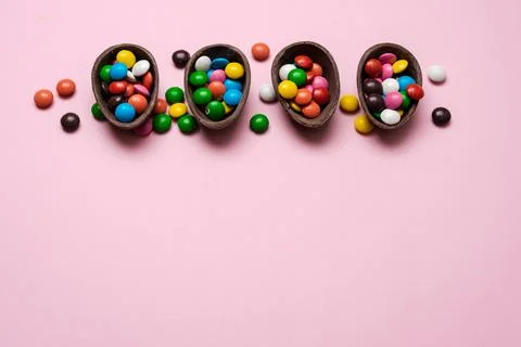 Happy Easter overhead with chocolate Easter eggs and decorations on a pink .. Stock Photos