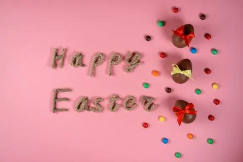 Happy Easter rope typography, chocolate eggs among colorful dragee on the pin Stock Photos