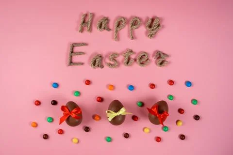 Happy Easter rope typography, chocolate eggs among colorful dragee on the pin Stock Photos