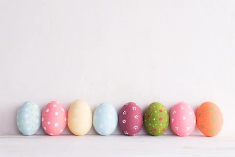 Happy easter! Row Easter eggs on bright white wooden background. Stock Photos