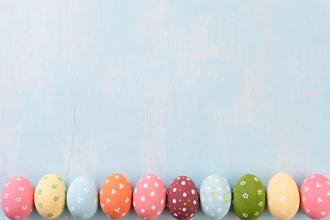 Happy easter! Row Easter eggs on bright blue wooden background. Stock Photos