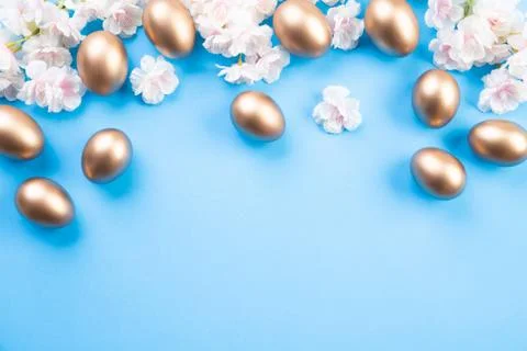 Happy easter! Row of golden Easter eggs with white and pink flower on blue  p Foto stock