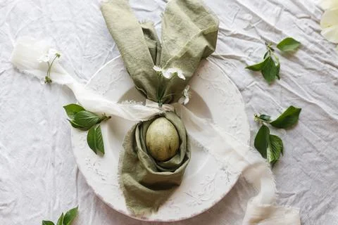 Happy Easter! Stylish dyed egg in bunny ears napkin and spring flowers  on .. Stockfoto's