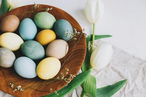 Happy Easter! Stylish Easter eggs in wooden plate, tulips and linen napkin .. Stock Photos