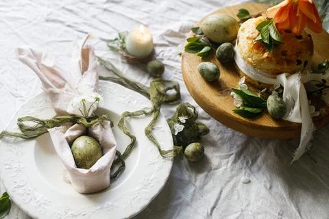 Happy Easter! Stylish eggs in bunny ears napkin on plate, easter cake on st.. 库存照片