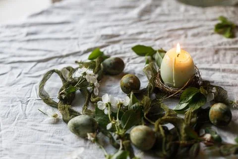 Happy Easter! Stylish green eggs and flowers on linen napkin and candle on .. Stock Photos