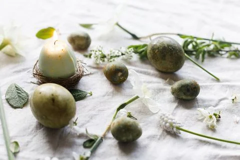 Happy Easter! Stylish natural dyed eggs, candle and spring flowers on linen.. Stock Photos