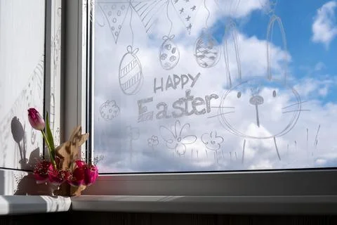 HAPPY EASTER text on creative painted window with white marker. Easter bunny Stock Photos