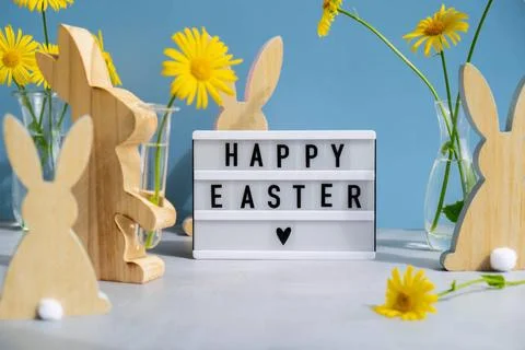 Happy Easter text on Lightbox with bunny wooden figures and fresh flowers.... Stock-Fotos