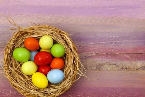 Happy easter text with painted eggs in wicker basket purple background copy.. Stock Photos