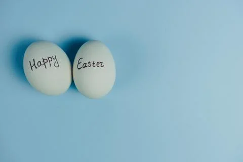 Happy Easter text on white eggs isolaed on blue background. Easter holiday Stock Photos
