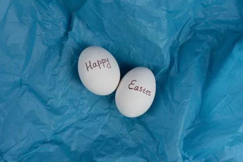 Happy Easter text on white eggs isolaed on blue background. Easter holiday Stock Photos