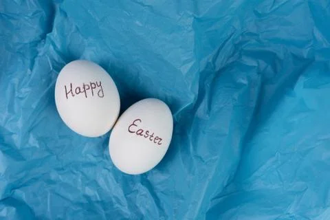 Happy Easter text on white eggs isolaed on blue background. Easter holiday Stock Photos