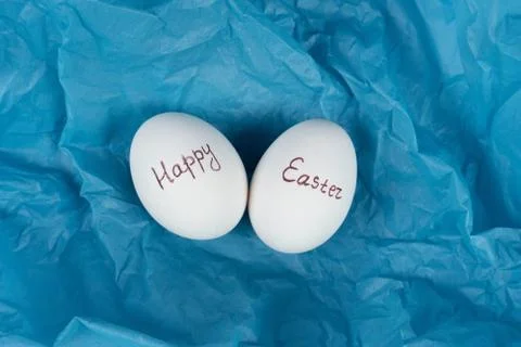 Happy Easter text on white eggs isolaed on blue background. Easter holiday Stock Photos
