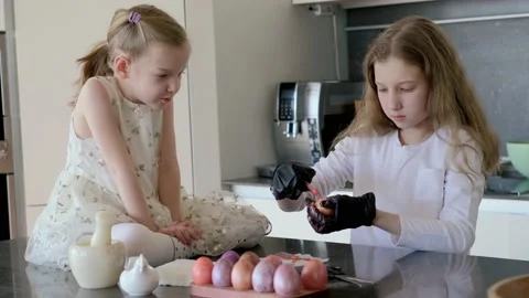 Happy easter. Two cute daughters coloring eggs for the traditional spring Stock Footage 220079512