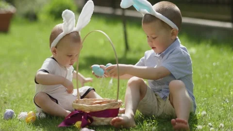 Happy Easter two little siblings sit green grass wear bunny ears play Easter egg Stock Footage 231297441