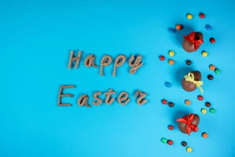 Happy Easter typography and chocolate eggs on the blue background. Celebratin Stock Photos