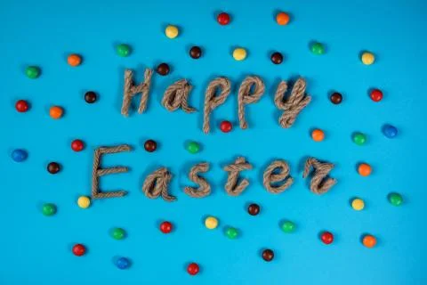 Happy Easter typography and dragee on the blue background. Stock Photos