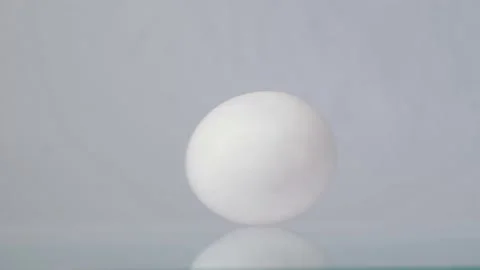 Happy Easter. White chicken egg spinning and rolling on a white background with Video stock 147414934