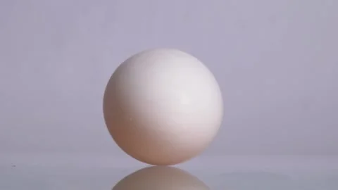 Happy Easter. White chicken egg spinning and rolling on a white background with Stock Footage 150560274