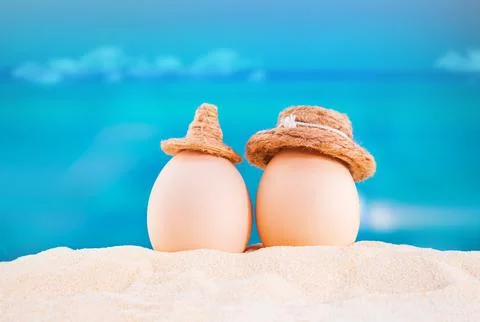 Happy easter. White eggs with hats on sandy beach of sea or ocean Stock Photos
