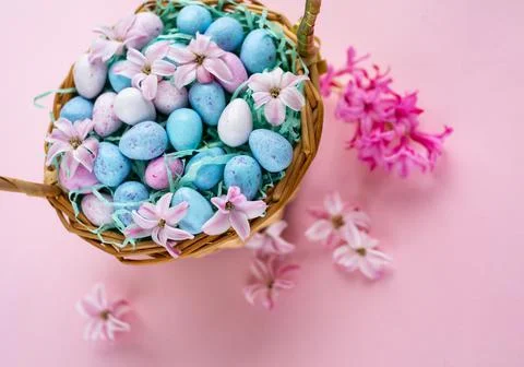 Happy Easter. Wicker basket with chocolat eggs and spring bright flowers, sel Stock Photos