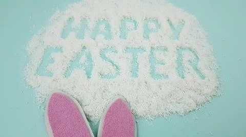 Happy Easter is written on a light blue background. easter bunny and ears are Stock Photos