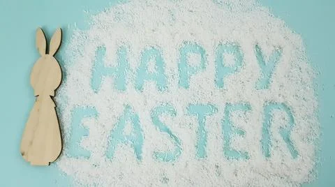 Happy Easter is written on a light blue background. easter bunny and ears are Stock Photos