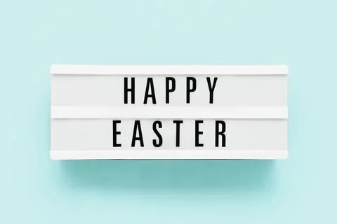 HAPPY EASTER written in light box on a light blue background. Top view Stock Photos