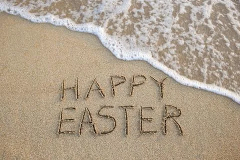 Happy easter written on sandy beach sea. Top view. Stock Photos