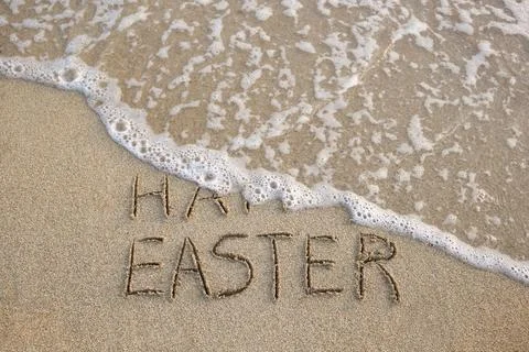 Happy easter written on sandy beach sea. Top view. Stock Photos