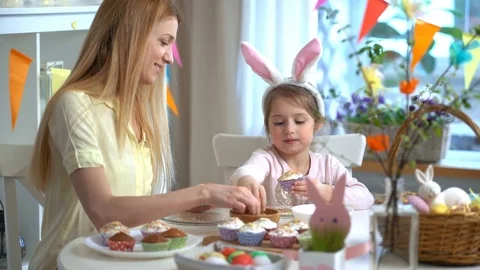 Happy Easter! Young mother and her little daughter cooking Easter cupcakes Stock Footage 84831974