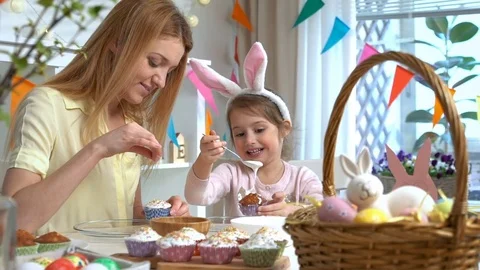 Happy Easter! Young mother and her little daughter cooking Easter cupcakes Stock Footage 84835321