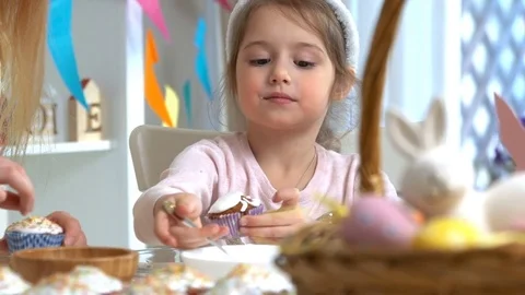 Happy Easter! Young mother and her little daughter cooking Easter cupcakes Stock Footage 84835598
