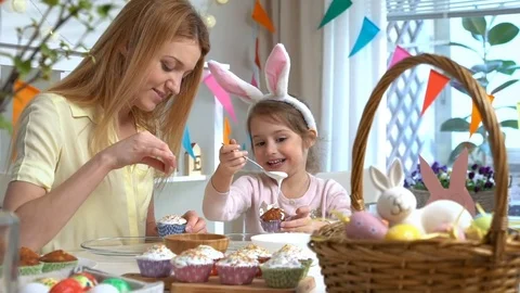 Happy Easter! Young mother and her little daughter cooking Easter cupcakes Stock Footage 84835741