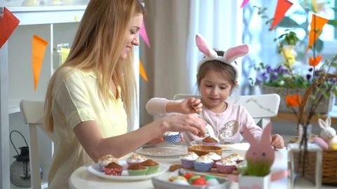 Happy Easter! Young mother and her little daughter cooking Easter cupcakes Stock Footage 84835857