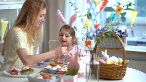 Happy Easter! Young mother and her little daughter cooking Easter cupcakes Stock Footage 84835921