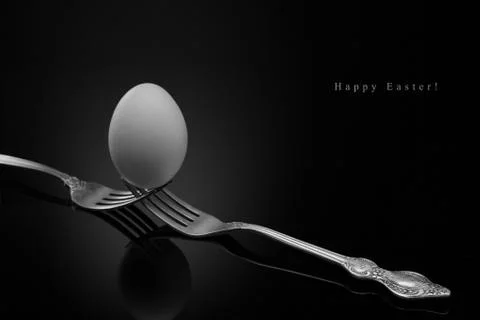 Happy Easter,white egg two forks ancient silver on a black background. Stock Photos